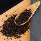 Japanese Wakoucha loose tea leaves on a wooden plank and in a wooden scoop.